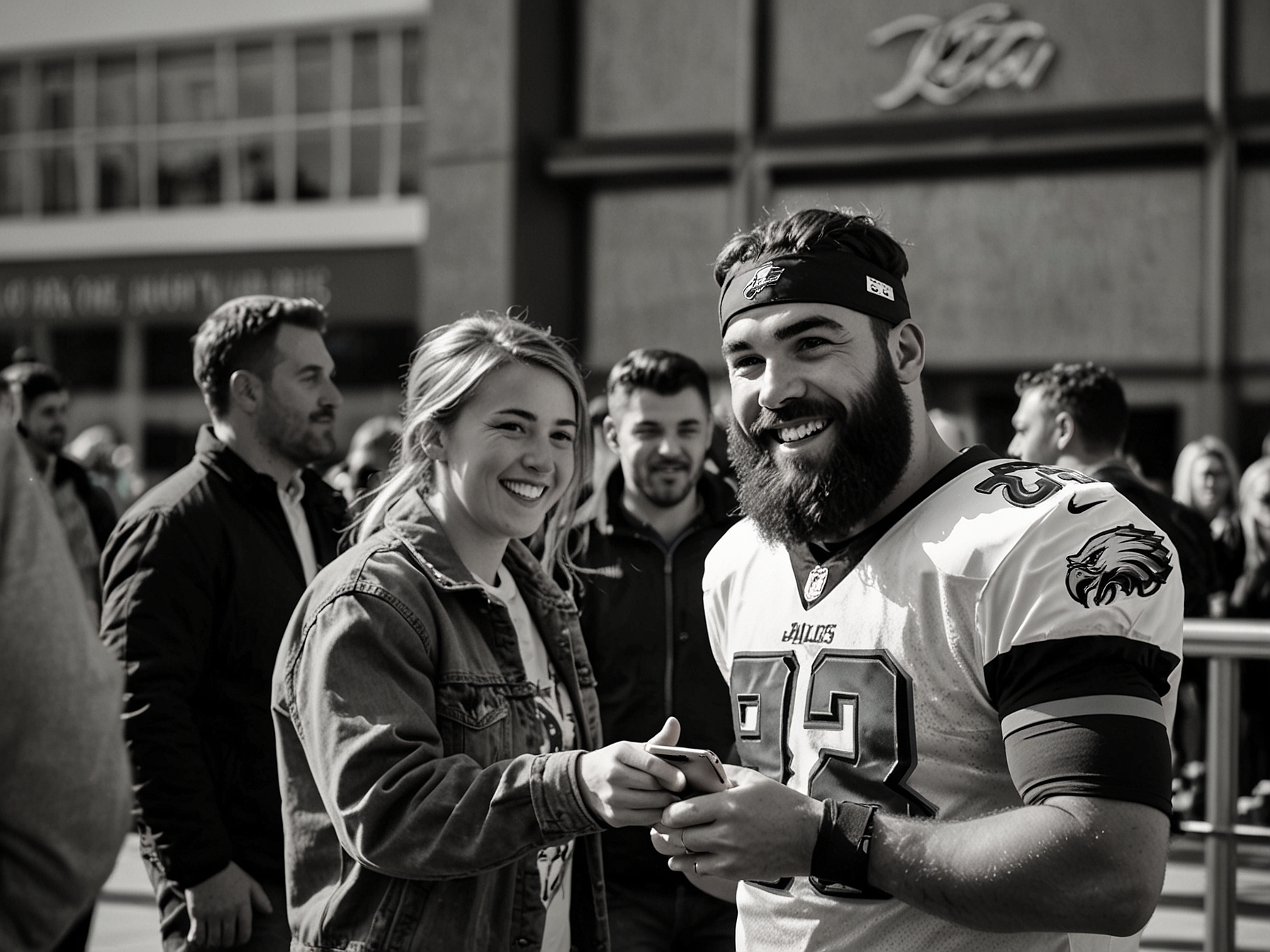 The young Eagles fan, eyes wide with excitement, meets Jason Kelce outside the O2 Arena. Kelce, smiling warmly, is signing the boy's jersey, surrounded by onlookers capturing the moment on their phones.