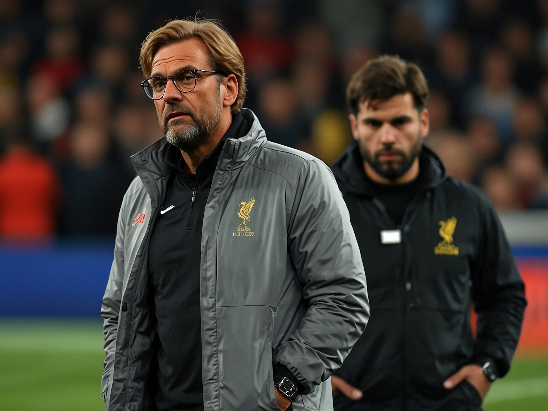 A concerned Jürgen Klopp watches from the sideline as Alisson limps off the pitch, highlighting the depth of emotion and pressure on Liverpool's management following the injury.