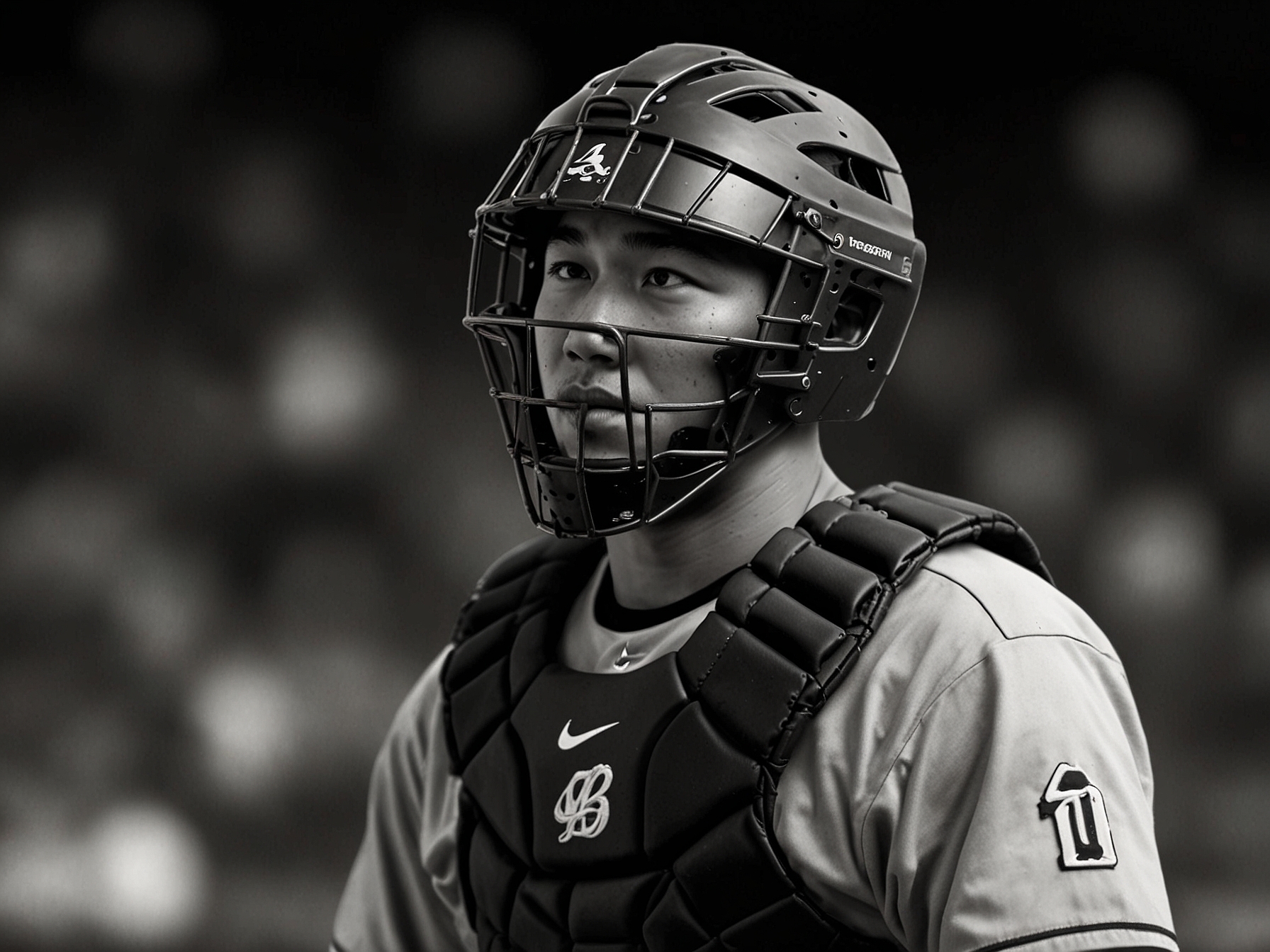 An action shot of Kyle Higashioka in his catcher's gear, preparing to receive a pitch during a game, showcasing his defensive skills and power as an MLB player.